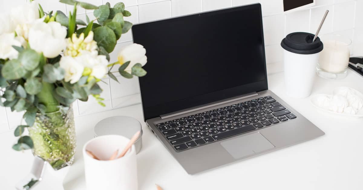 Desk with laptop, coffee, and flowers